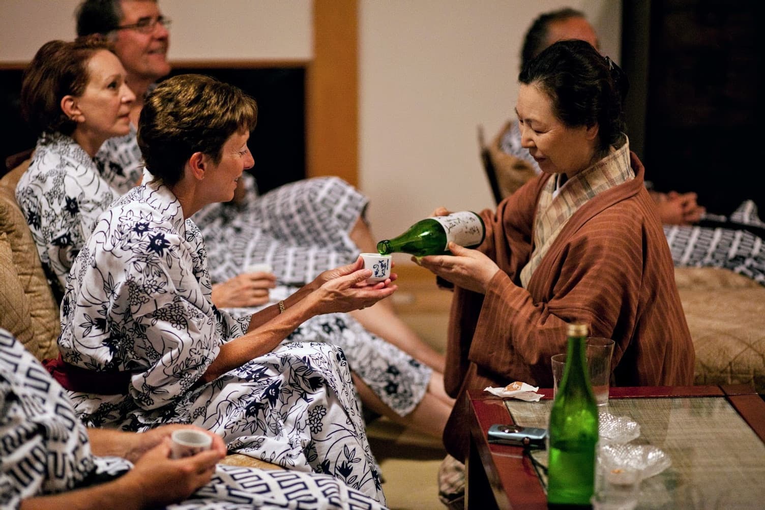 A ryokan host serving sake to guests captures the essence of Japanese hospitality.